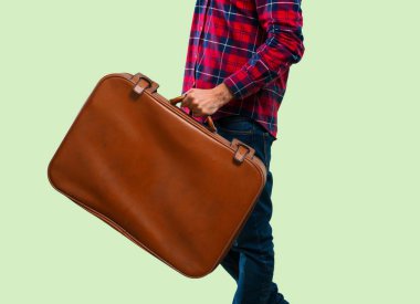 Yakışıklı adam bir vintage çanta yeşil arka plan üzerinde tutan