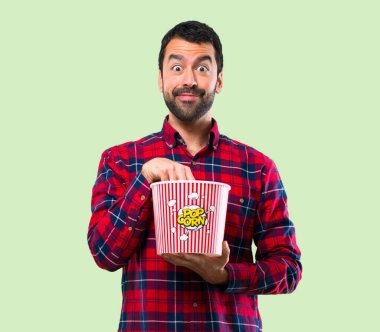 Yakışıklı adam yeme popcorns yeşil zemin üzerine