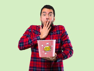 Yakışıklı adam yeme popcorns yeşil zemin üzerine