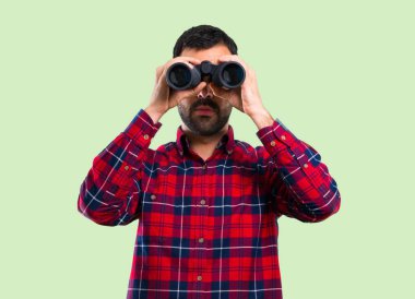 Yeşil arka plan üzerinde siyah dürbünlü yakışıklı adam