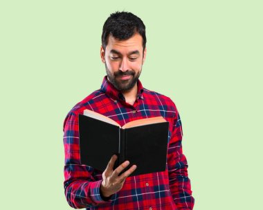 Holding ve yeşil zemin üzerine bir kitap okuma yakışıklı adam
