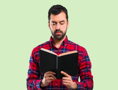 Holding ve yeşil zemin üzerine bir kitap okuma yakışıklı adam