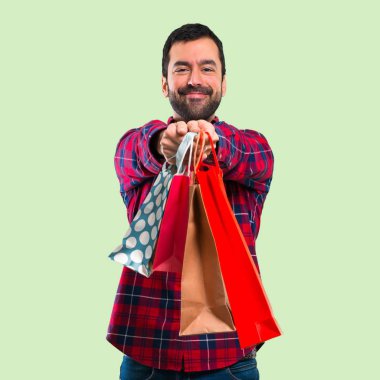 Yakışıklı adam alışveriş torbaları bir sürü yeşil arka plan üzerinde tutan