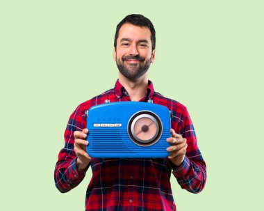 Yakışıklı adam mavi bir vintage radyo yeşil arka plan üzerinde tutan