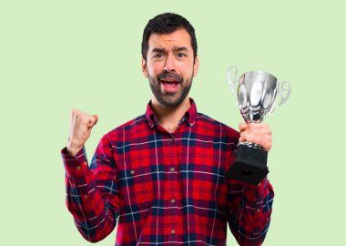 Yakışıklı adam bir kupa yeşil arka plan üzerinde tutan