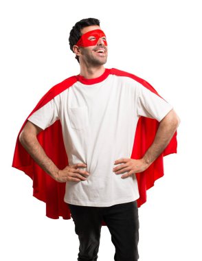 Silah, kalça ile poz ve izole beyaz zemin üzerine gülen maske ve kırmızı pelerin adamla süper kahraman