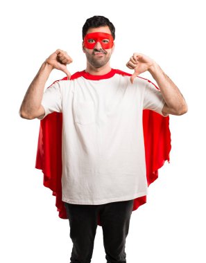 Süper kahraman maske ve kırmızı pelerin başparmak aşağı her iki el ile gösterilen adamla. Negatif ifade izole beyaz arka plan üzerinde