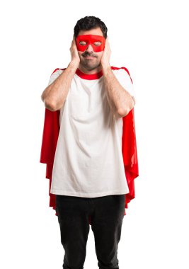 Süper kahraman maske ve kırmızı pelerin her iki kulak elleriyle kapsayan adamla. Hayal kırıklığı ifade izole beyaz arka plan üzerinde