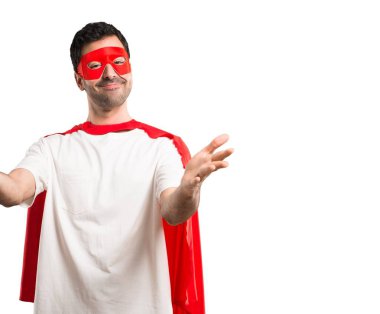 Süper kahraman adam sunulması ve el ile gelmek davet maskesi ve kırmızı pelerin. Mutlu izole beyaz arka plan üzerinde geldi