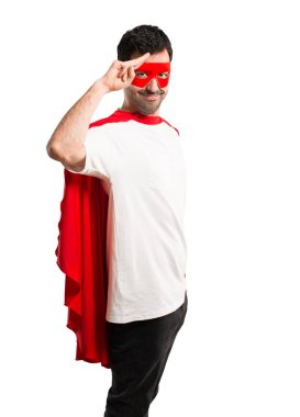 Süper kahraman maske ve kırmızı pelerin ile mutlu ifade izole beyaz arka plan üzerinde el ile selamlayan adamla