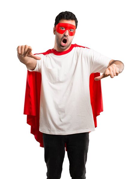 Superhero man with mask and red cape pointing with finger at someone and laughing a lot on isolated white background