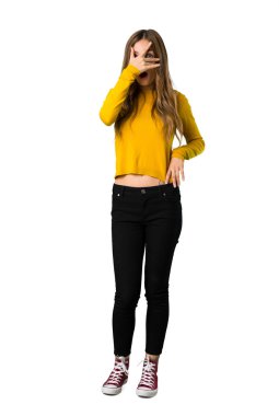 Sürpriz ve izole beyaz zemin üzerine şok yüz ifadesi ile sarı kazaklı genç bir kızın tam uzunlukta bir atış