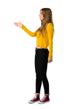 Sarı kazak el sıkışma izole beyaz arka plan üzerinde iyi bir anlaşma sonra genç bir kızla tam uzunlukta bir kadeh