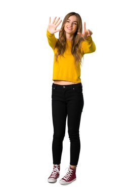 Bir genç kızın sarı kazaklı yedi ile izole beyaz arka plan üzerinde parmak sayma tam uzunlukta bir atış