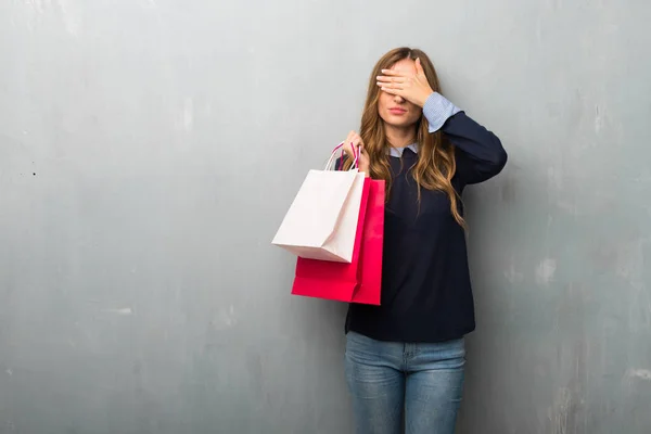 Girl with shopping bags covering eyes by hands. Do not want to see something