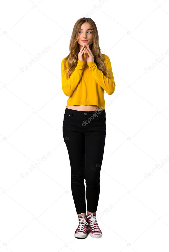 A full-length shot of a young girl with yellow sweater scheming something on isolated white background