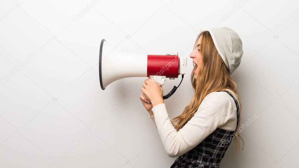 Fashionably woman wearing hat shouting through a megaphone to announce something in lateral position