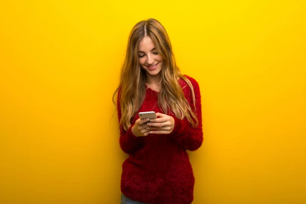 Chica Joven Sobre Fondo Amarillo Vibrante Enviando Mensaje Con Móvil — Foto de Stock