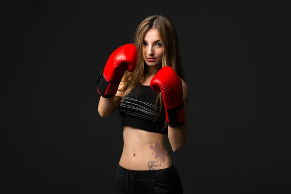 Sport woman with boxing gloves on dark background