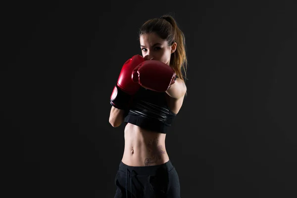 Sport woman with boxing gloves on dark background