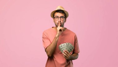 Bir işaret parmağını ağzına koyarak, pembe arka plan sessizlik jest gösteren faturaları tutan adam