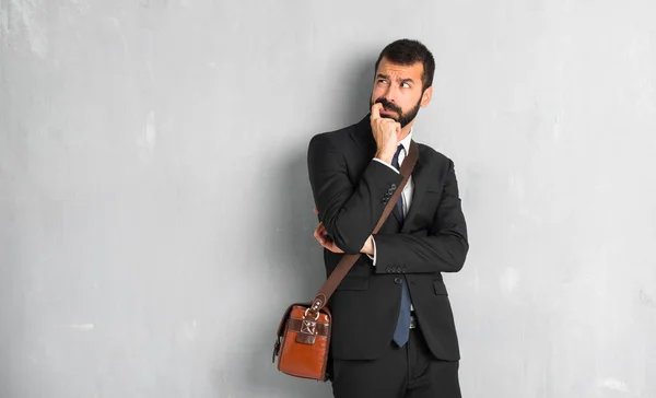 Businessman with beard having doubts while looking up