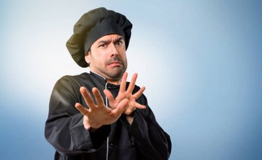 Şef biri siyah üniformalı biraz gergin ve korkmuş uzanan eller için mavi arka plan üzerine açık