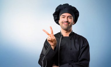 Şef adam siyah üniforma mutlu ve sayım iki parmak üzerinde mavi arka plan ile