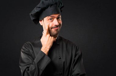 Şef adam ayakta ve siyah arka plan üzerine parmağınızla göz açma ön seyir siyah üniformalı