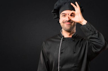 Siyah üniformalı erkeklere Şef komik ve çılgın yüz duygu siyah arka plan üzerine yapar.