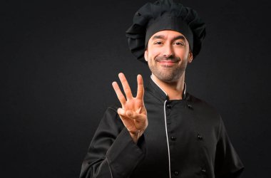 Siyah üniforma mutlu ve sayım üç siyah arka plan üzerine parmağınızla erkekte Şef