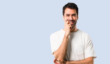 Beyaz gömlek izole mavi zemin üzerine tatlı bir ifade ile gülümseyen genç adamla