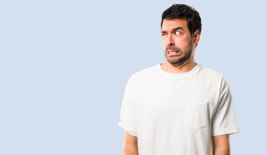 Biraz gergin ve korkmuş diş izole mavi zemin üzerine basarak beyaz gömlek genç adam.