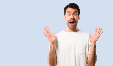 Sürpriz ve şok yüz ifadesi ile beyaz gömlek olan genç adam. Ağzı açık çünkü izole mavi arka plan üzerinde olanlar beklemek değil