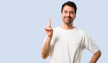 Delikanlı ile gösterilen ve işareti en iyi izole mavi zemin üzerine bir parmak kaldırma beyaz gömlek