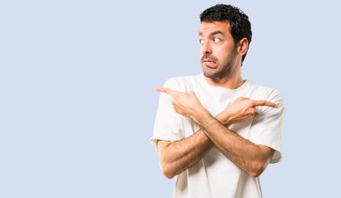 Beyaz gömlek şüpheleri Laterallerin işaret eden genç adam. Kararsız insan izole mavi arka plan üzerinde