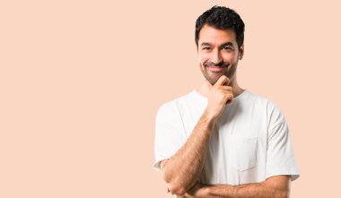 Beyaz gömlek gülümseyen ve öne doğru emin yüz ile izole koyu sarı arka plan üzerinde seyir ile genç adam