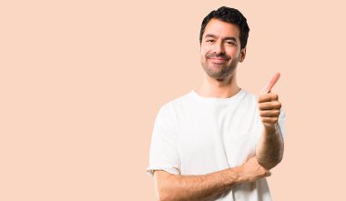 Jest Yaşasın vererek ve çünkü iyi bir şey izole koyu sarı arka plan üzerinde oldu gülümseyen beyaz gömlek ile genç adam