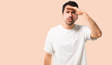 Bir şey üzerinde izole koyu sarı arka plan bakmak için genç adam beyaz gömlek uzakta el ile seyir ile