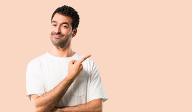 Genç adam beyaz gömlek bakarken bir ürün ya da bir fikir sunmak için parmağını bile yanında işaret ile ileri üzerinde gülümseyen izole koyu sarı arka plan