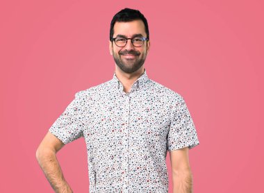 Gözlüklü arms adlı kalça üzerinde pembe bir arka plan ile poz yakışıklı adam