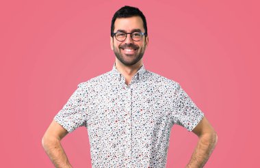 Gözlüklü arms adlı kalça üzerinde pembe bir arka plan ile poz yakışıklı adam