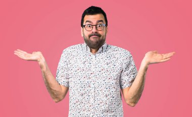 Yakışıklı adam gözlüklü şüpheleri ve pembe bir arka plan üzerinde karıştırmayın yüz ifadesi ile