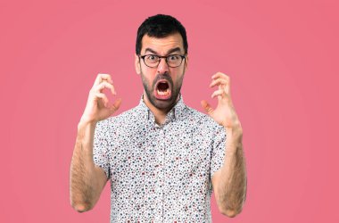 Gözlüklü rahatsız ve kızgın pembe bir arka plan üzerinde öfkeli jest olarak yakışıklı adam