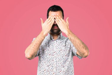 Yakışıklı adam gözlüklü gözlerle kapsayan, pembe arka plan eller