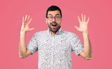 Sürpriz ve pembe bir arka plan üzerinde şok yüz ifadesi ile gözlüklü yakışıklı adam