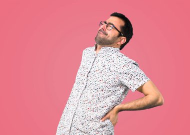 Pembe bir arka plan üzerinde sırt ağrısı ile gözlüklü yakışıklı adam