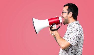 Gözlüklü bir megafon, pembe arka plan tutan yakışıklı adam