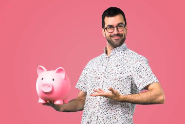 Gözlüklü bir servet pembe bir arka plan üzerinde tutarak yakışıklı adam