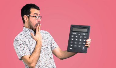 Bir hesap makinesi, pembe arka plan tutan gözlüklü yakışıklı adam
